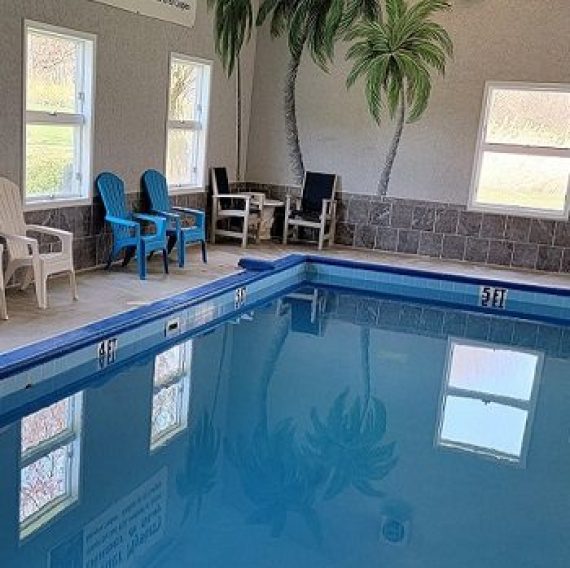 Indoor heated swimming pool with seating area at Brook Pointe Resort in Syracuse, Indiana