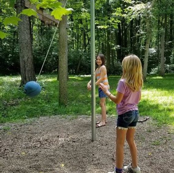 Guests playing tetherball outdoor yard game in the Family Cove at Brook Pointe Resort in Syracuse, Indiana